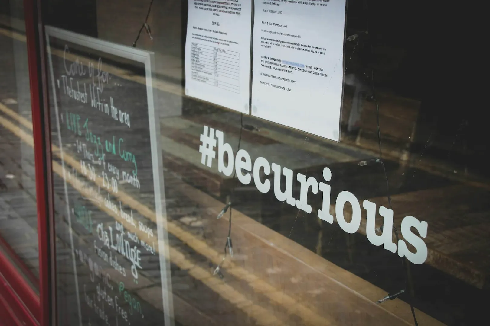 Imagem de uma vitrine transparente com a escrita #becurious em adesivo branco